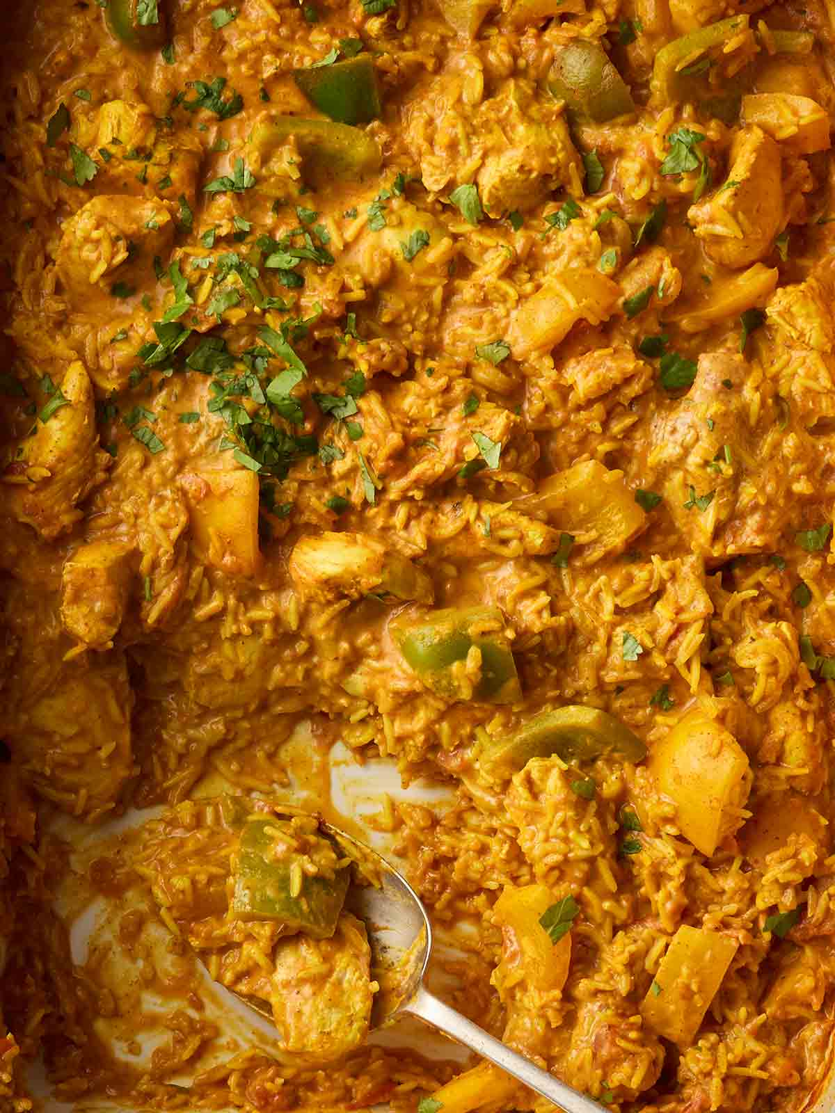 A one pan chicken tikka and rice dish, with a spoon ready to serve up.
