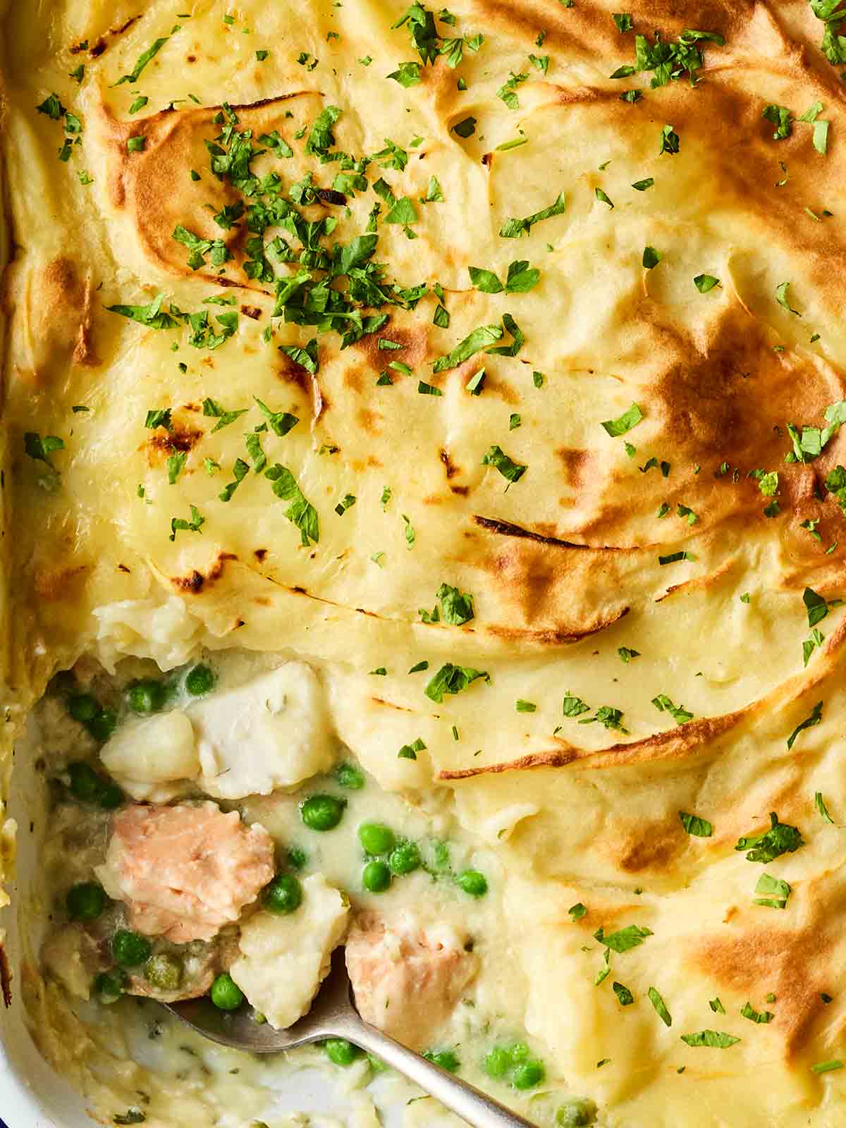 A close look at a cooked fish pie, with a piece missing as it's served up for dinner.