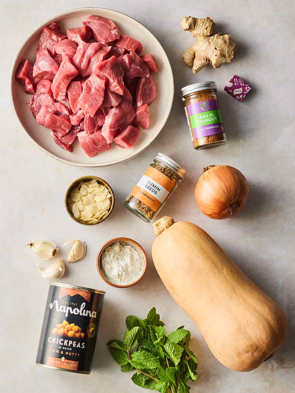 The raw ingredients for making a Lamb Tagine laid out on a white surface.