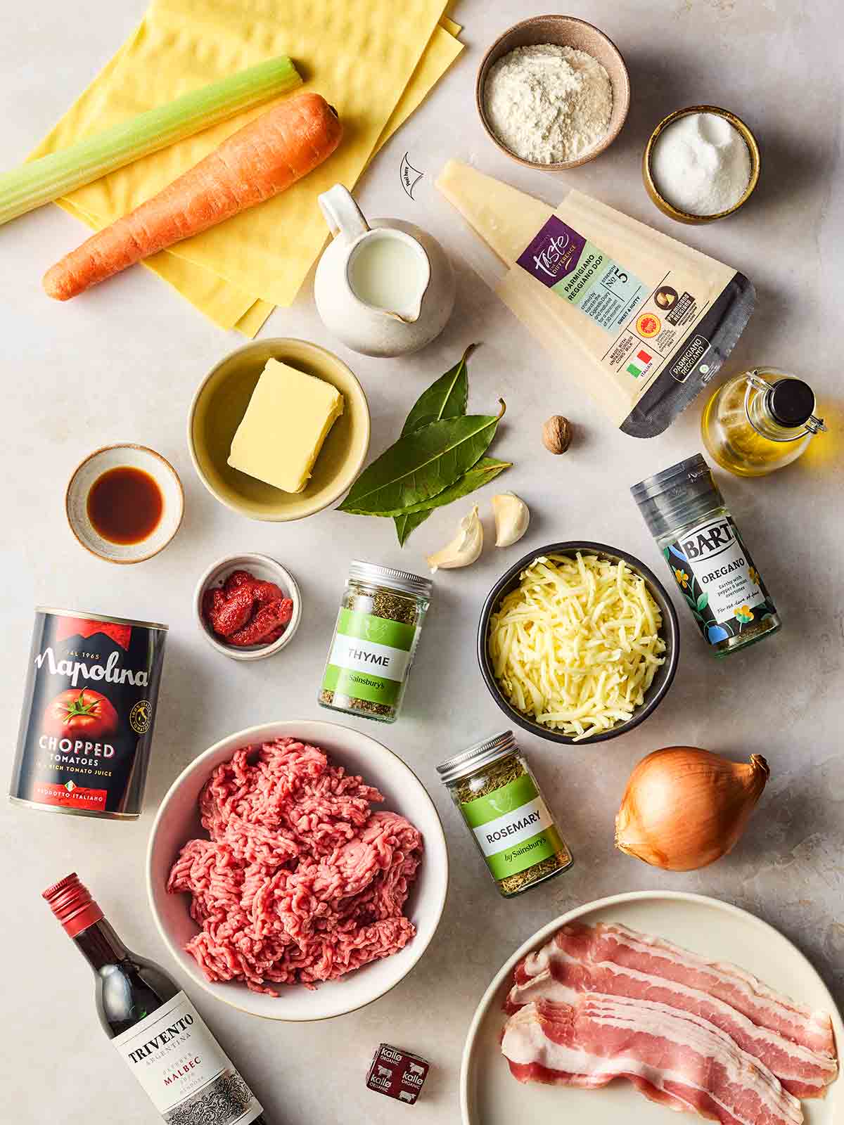 The ingredients for a classic lasagne recipe laid out on a white surface.