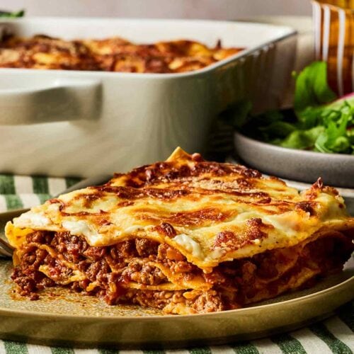 A classic beef lasagne slice on a plate, ready to eat, showing layers of ragu and pasta.