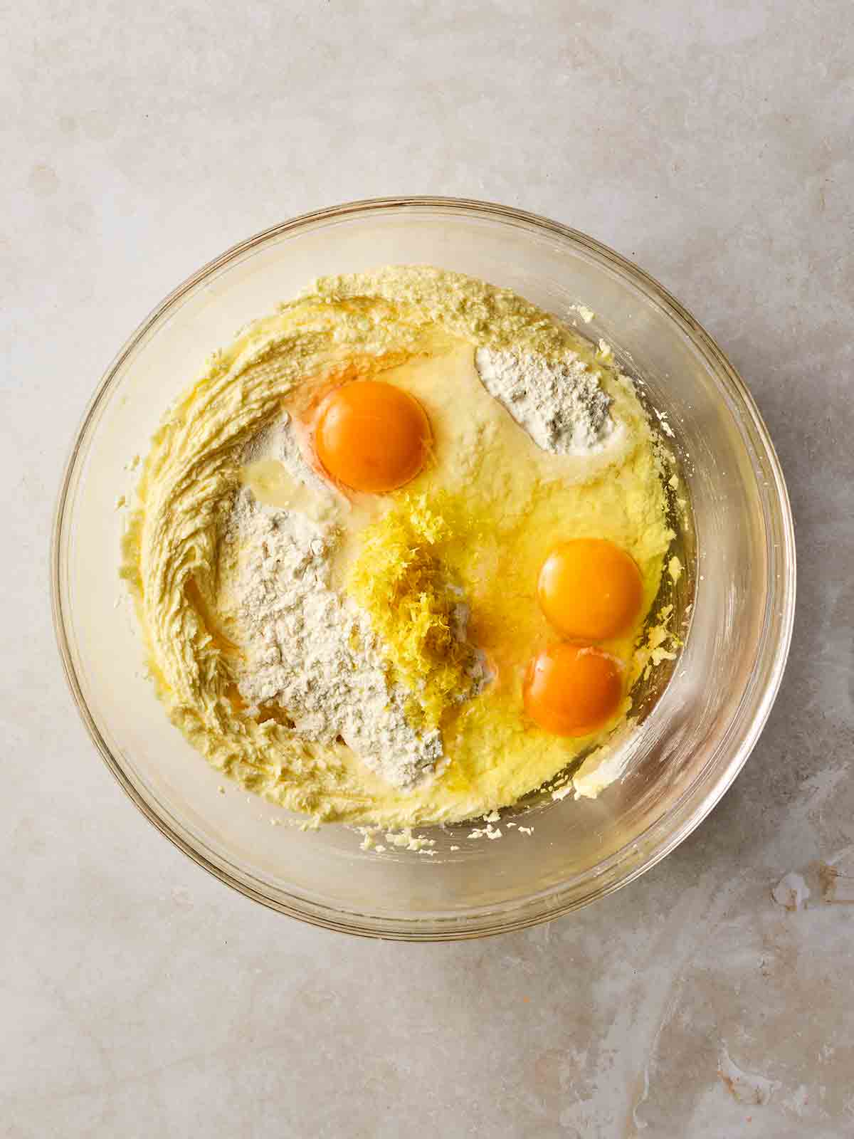 A cupcake batter with eggs on top in a glass bowl for a step-by-step recipe.