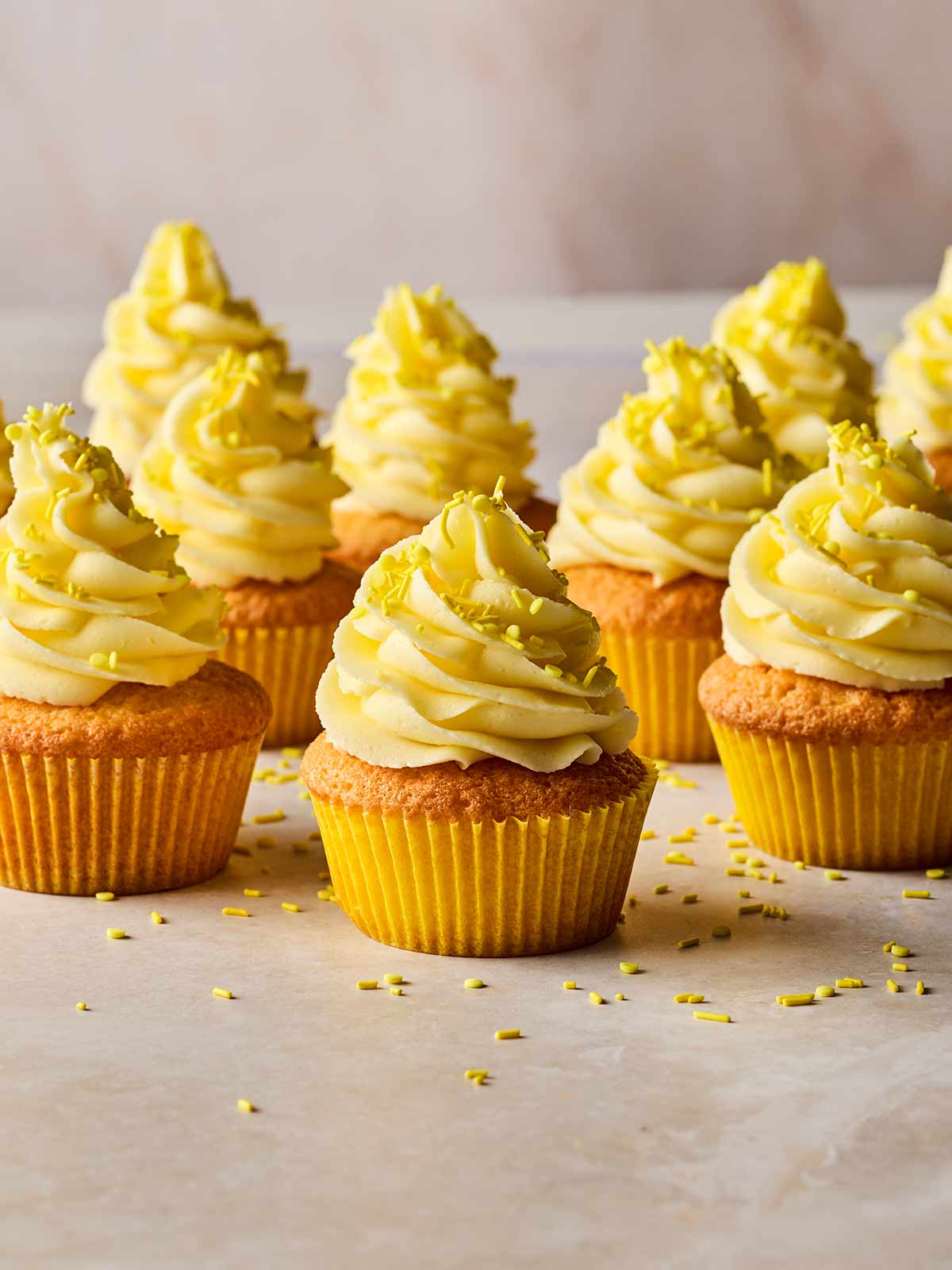 Rows of lemon cupcakes on a white surface.