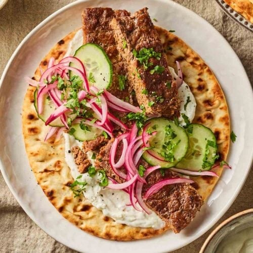 A close up of the viral social media recipe Sheet Pan Kebabs, made up with salad and flatbread, on a table ready to eat.