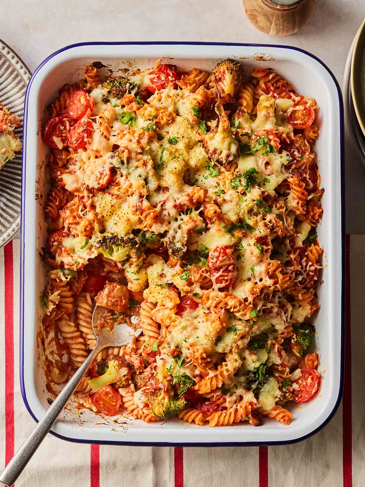An oven dish on a table, with tuna pasta bake in, a portion missing having been served.