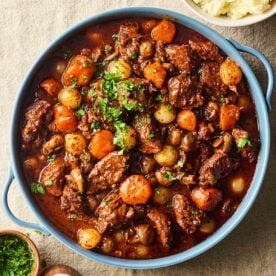 A large pot of homemade Beef Bourguignon, on a table, ready to serve with mashed potatoes.