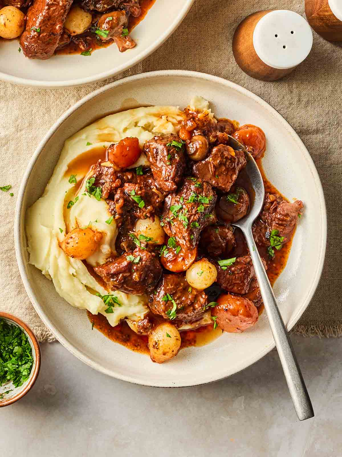 A dish of beef bourguignon with mashed potato, with a spoon in, ready to eat.