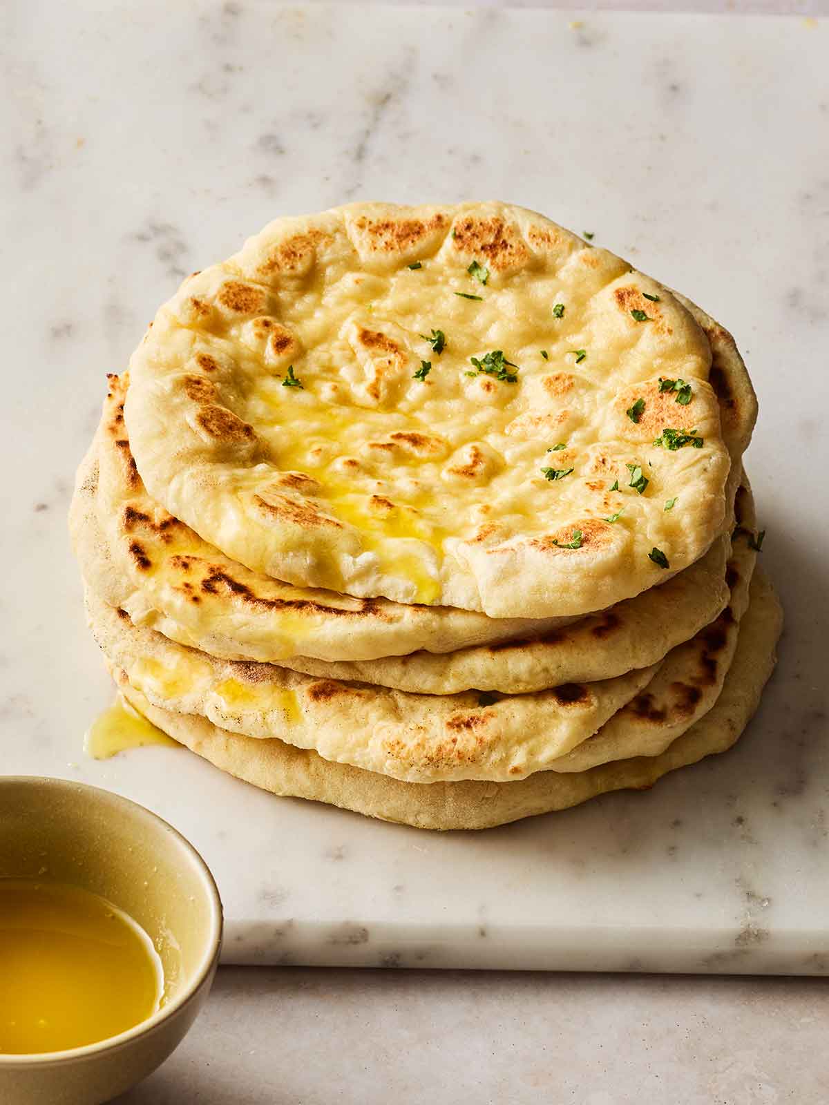 A pile of round homemade flatbreads on a white surface.