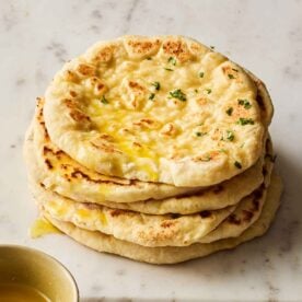 A pile of soft flatbreads, made from scratch, on a white marble surface.
