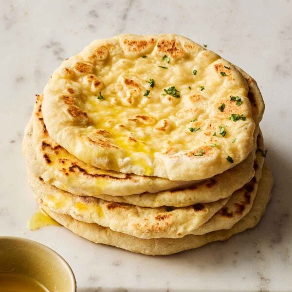 A pile of soft flatbreads, made from scratch, on a white marble surface.