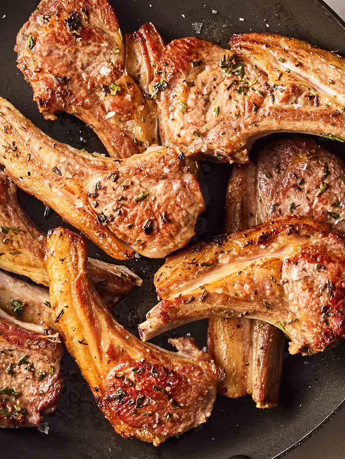 A pan with lots of cooked lamb chops, browned and succulent.