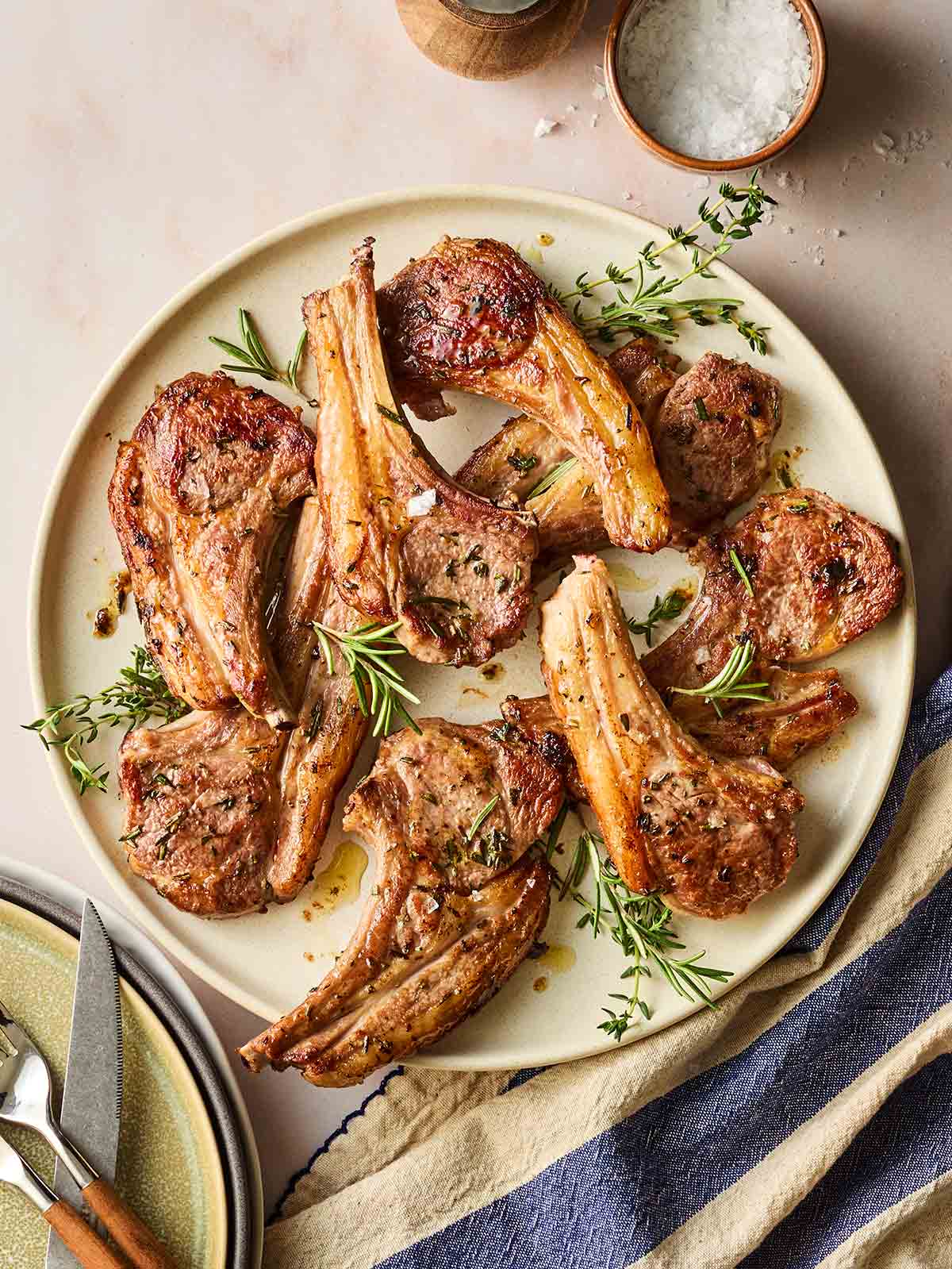 A plate of cooked lamb chop with herbs, looking juicy and delicious, on a table.