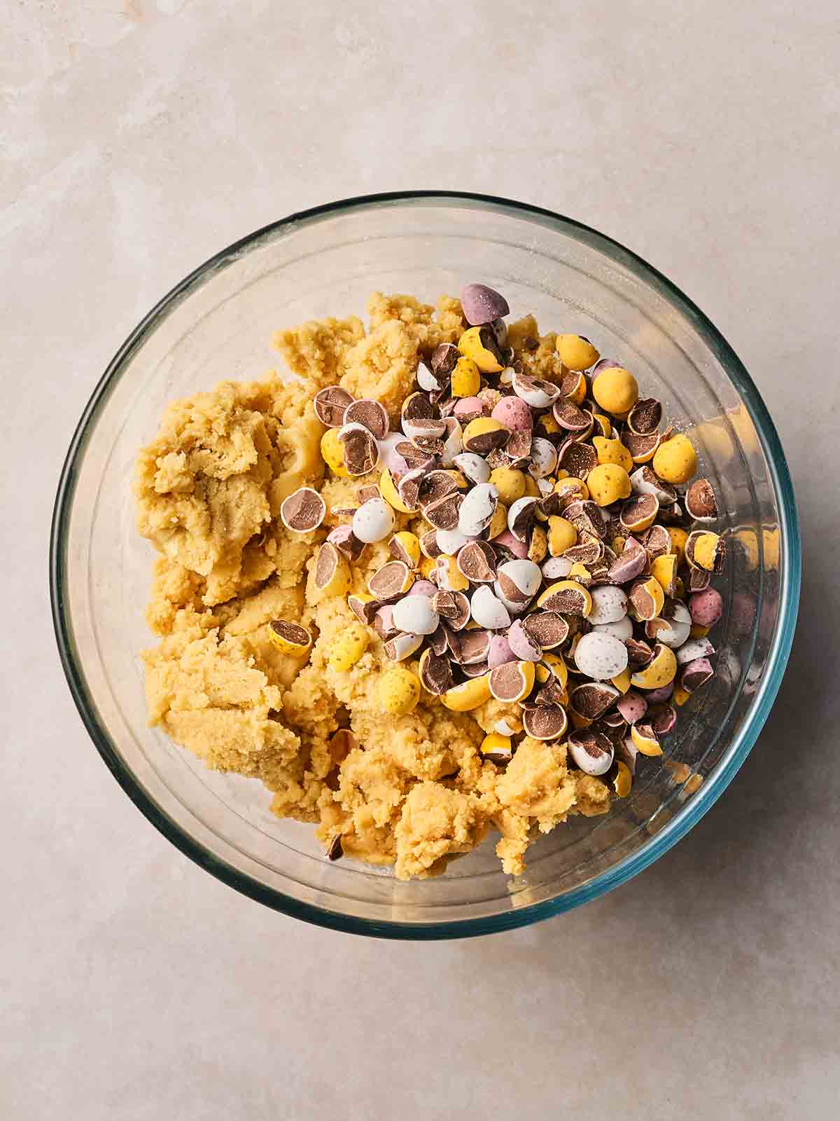 A cookie dough mix in a glass bowl with crushed up Cadbury's mini eggs.