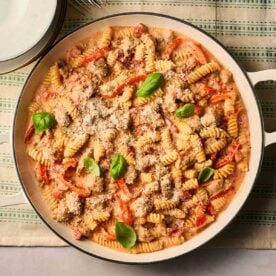 A close up of a pan of Sausage pasta, ready to serve at the table.