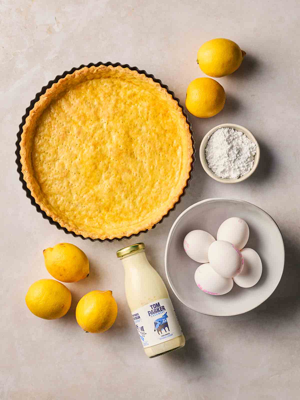 The ingredients for making a Lemon Tart on a white surface.