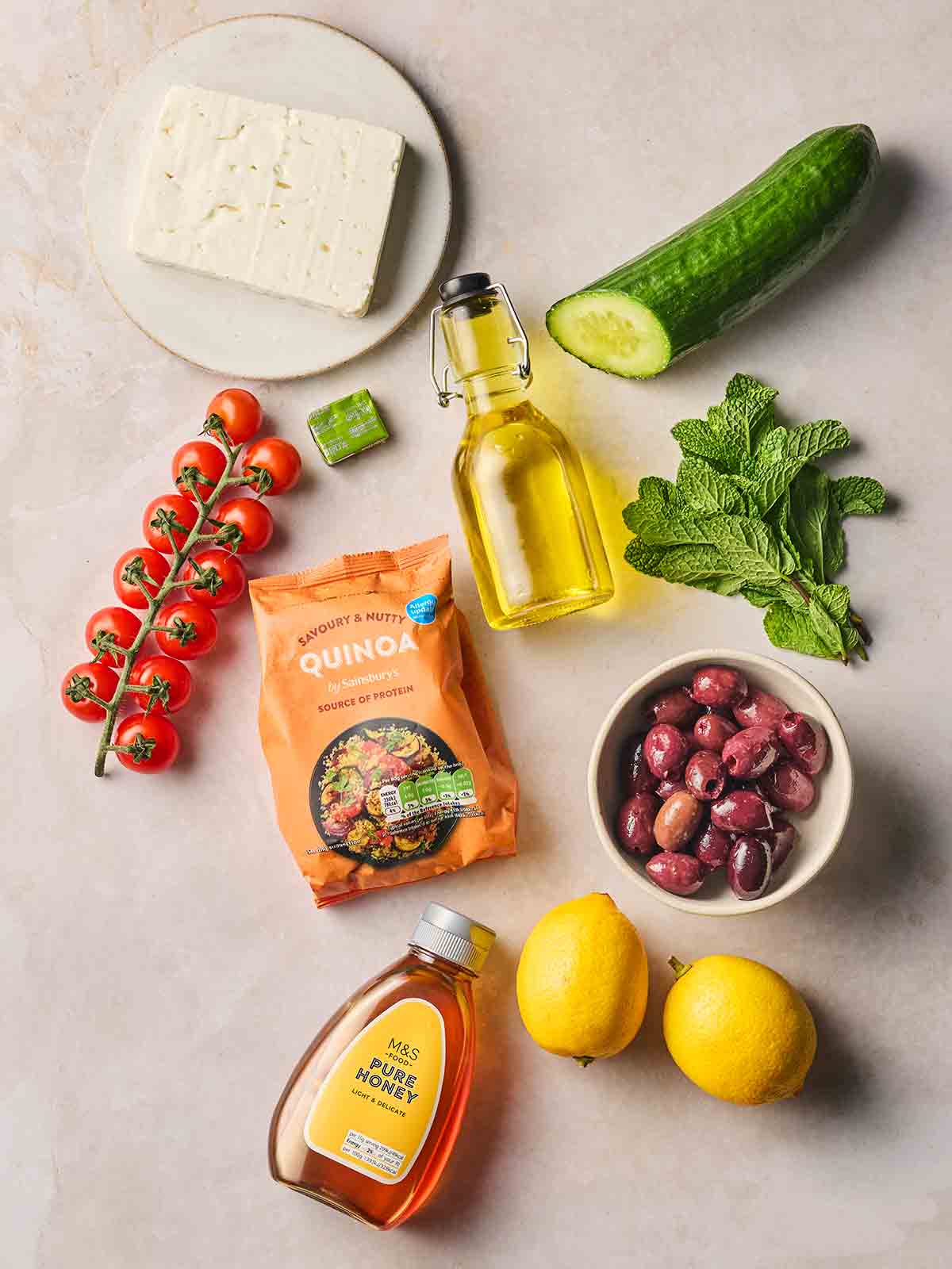 The ingredients for a Quinoa Salad laid on a white surface.