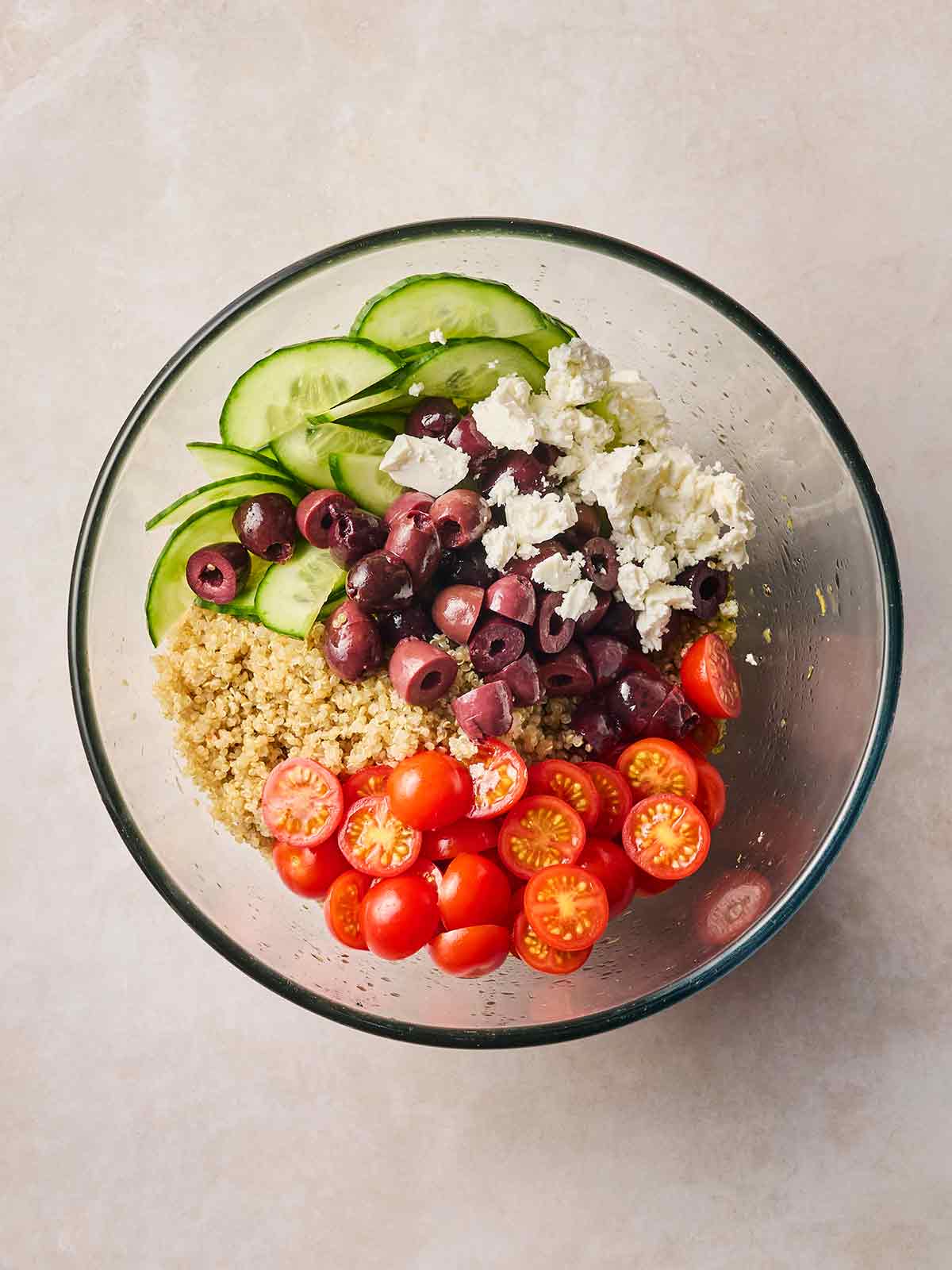The ingredients for making a Quinoa Salad all in one glass bowl, ready to be mixed.