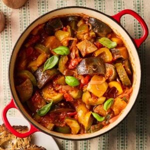 A classic French style stew, Ratatouille, in a big pan on a table, ready to serve with crusty bread at the side.