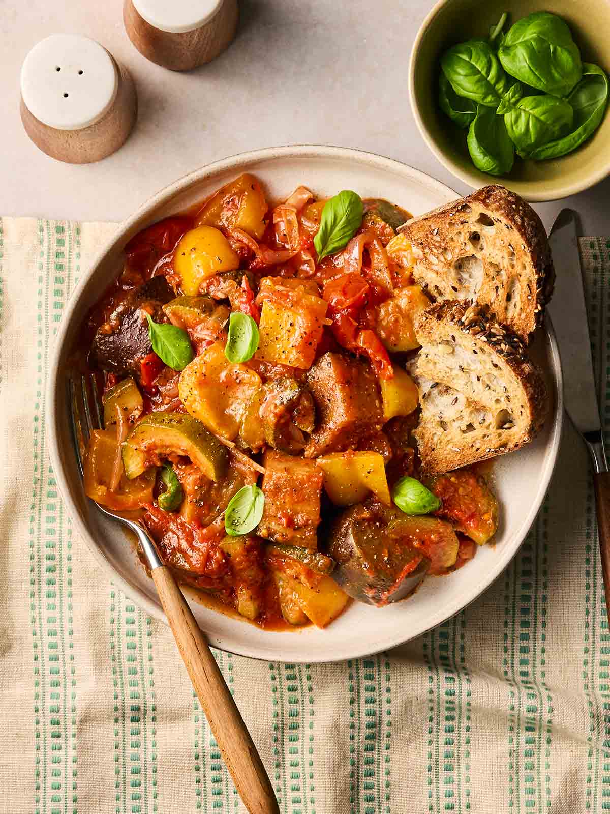 A plate of classic Ratatouille with crusty bread, a fork, ready to tuck in.
