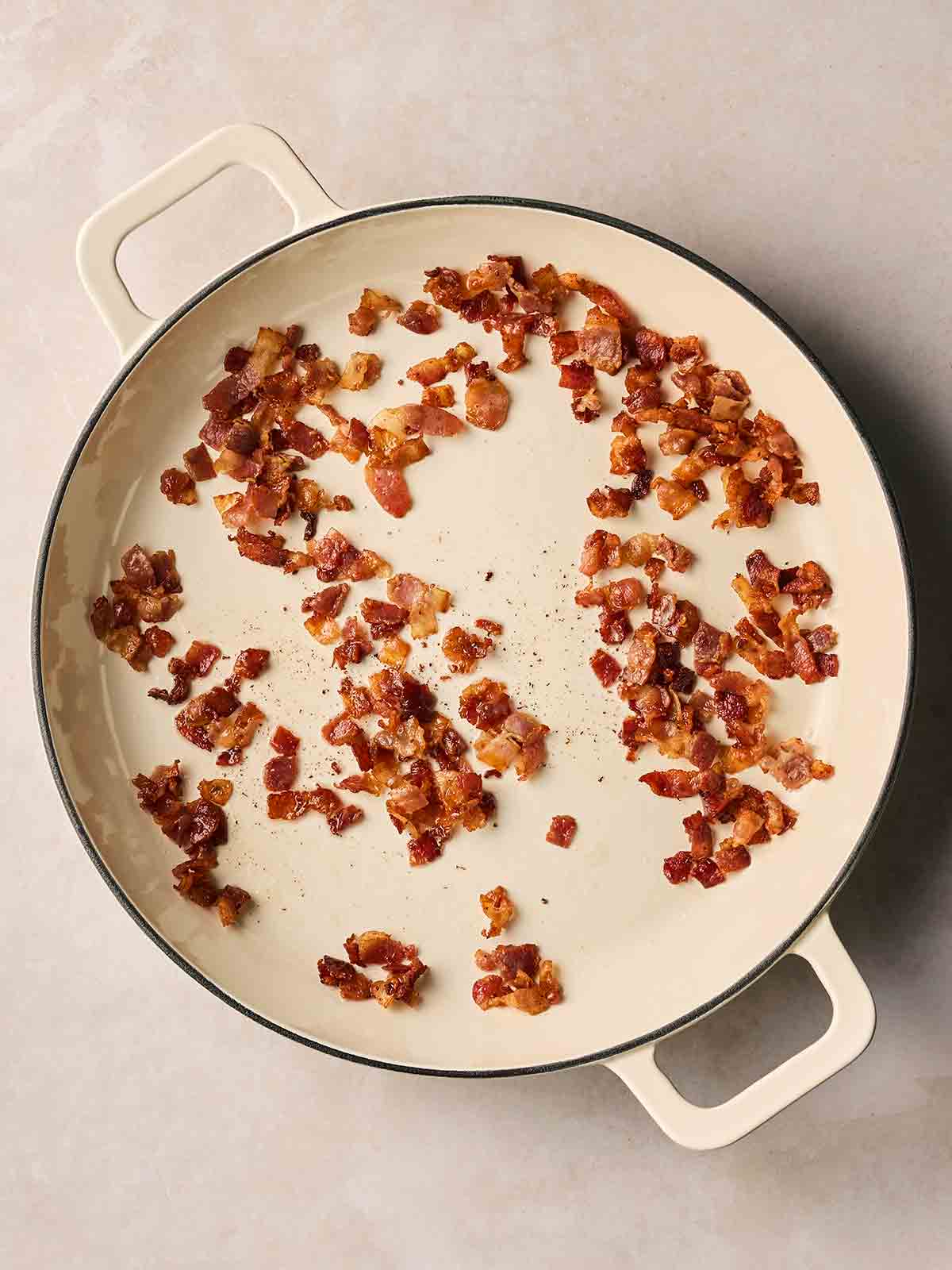 A pan with frying cubes of bacon in.