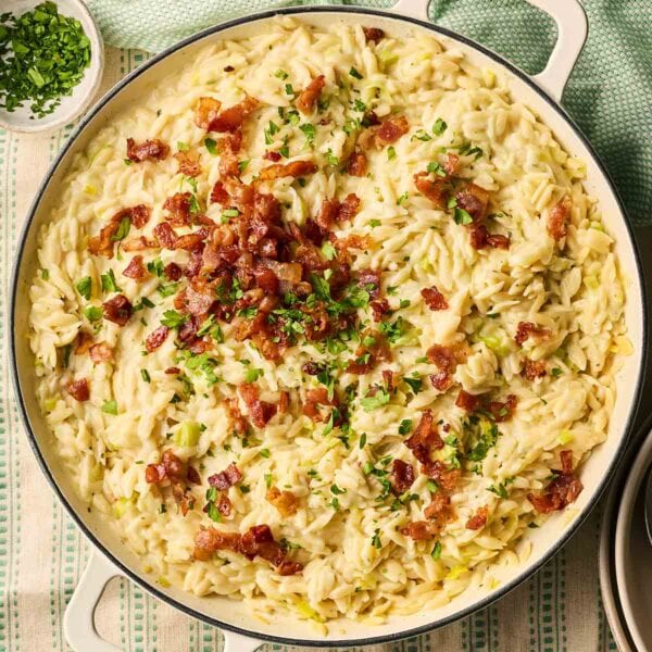 A large pan on a table filled with bacon and leek orzo pasta.