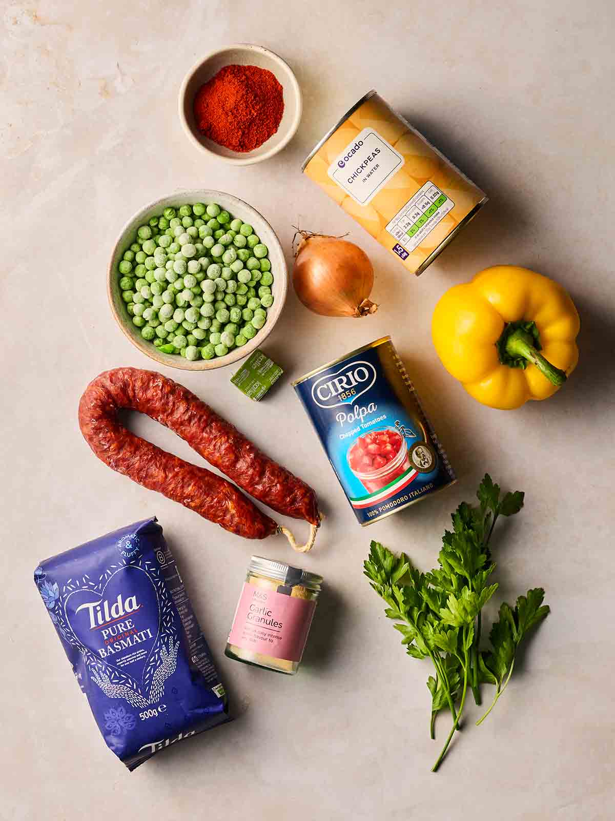 The ingredients for making a dump and bake recipe, Chorizo Rice, all laid out on a white surface.