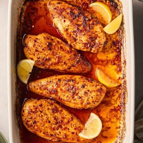 A dish of baked chicken with a chilli and honey marinade, ready to serve onto plates from an oven dish.