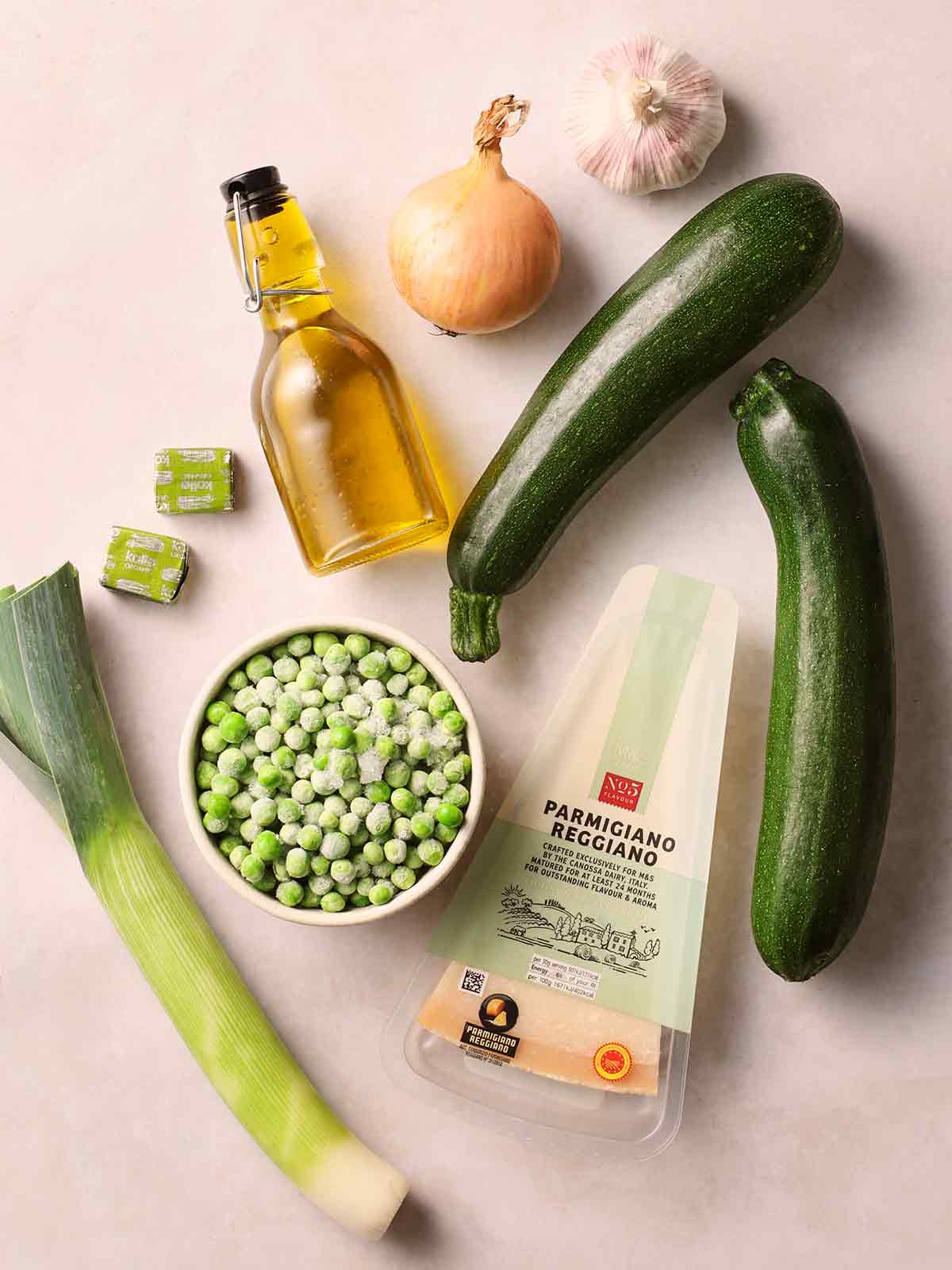The raw ingredients for making courgette soup laid out on a white surface.
