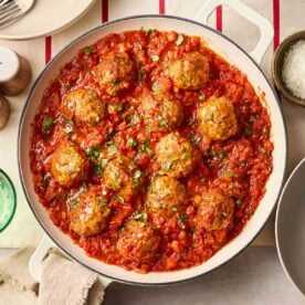 Classic meatballs in a tomato sauce, in a white pan on a set table.