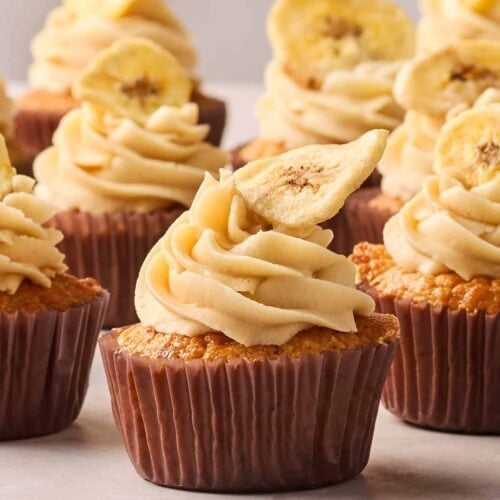 A side angle of homemade banana cupcakes, on a white surface and a white background.