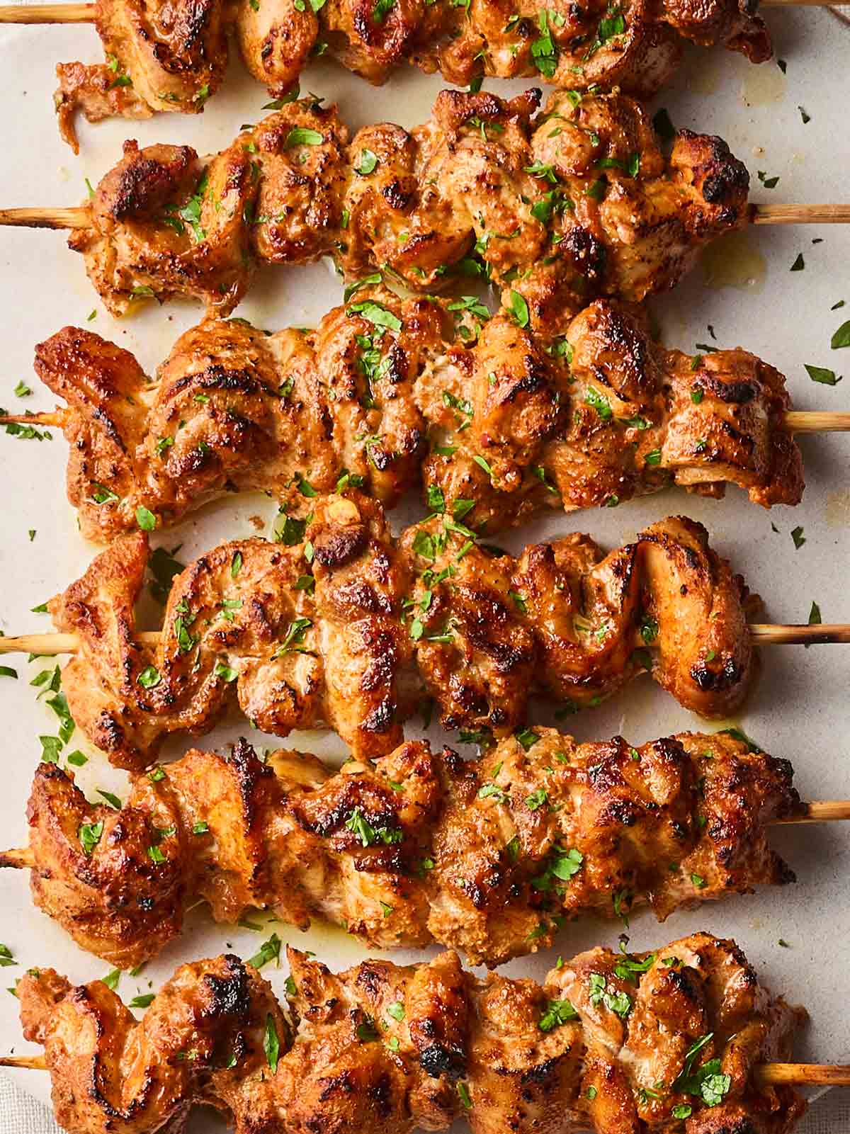 A line of cooked chicken skewers with a white background.