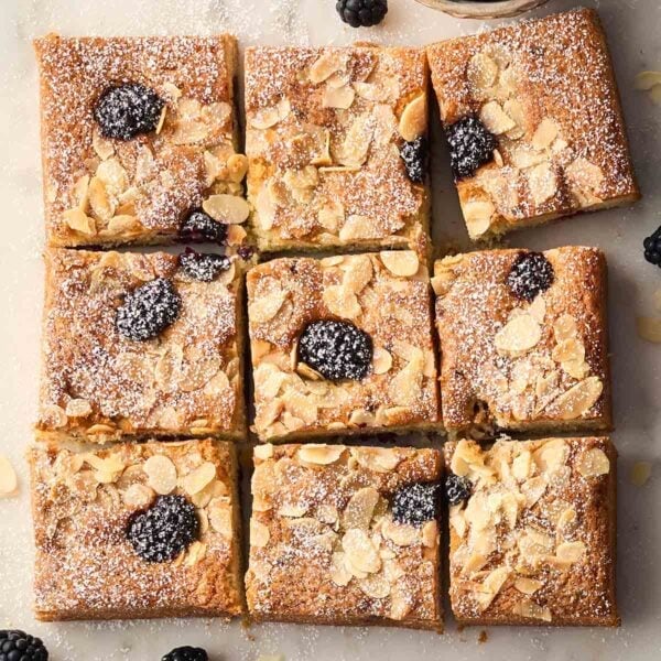A square blackberry cake cut into nine pieces, ready to eat.