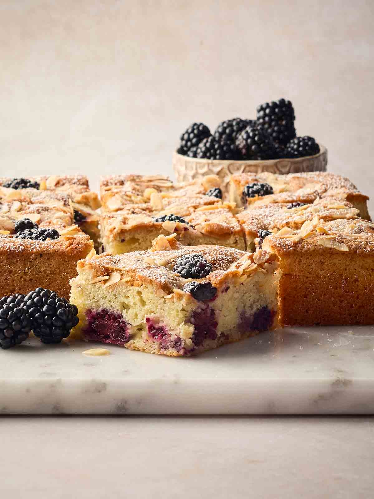 A side view of a blackberry cake, cut into squares, ready to eat.